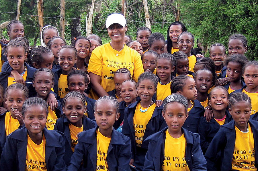 Lily Yoseph surrounded by student girls in yellow and blue shirts.