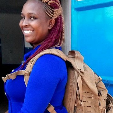 Photo © by Monty Munford Smiling woman in a blue shirt with a big backpack