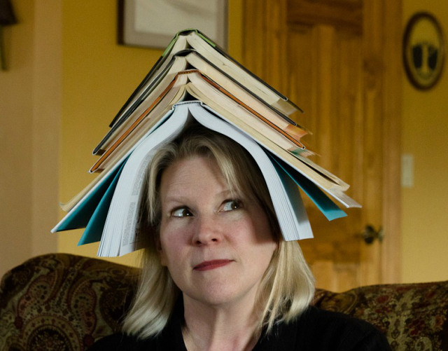 Woman with books stacked on her head.